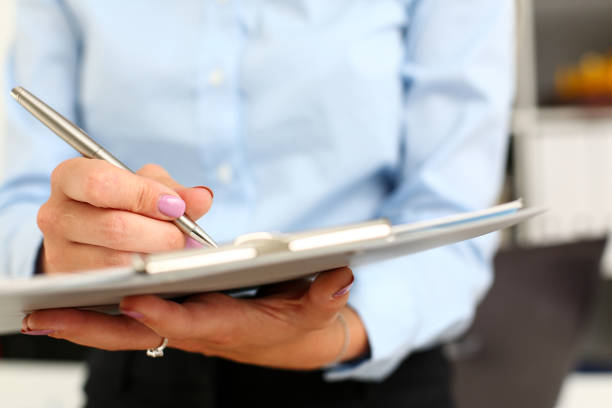 Female arm in suit hold silver pen and pad making note in office closeup. Deal consult, delivery signature, financial inspector job, fill survey form, discuss strategy, project negotiation concept