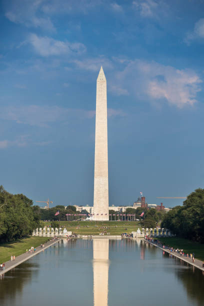 Washington Monument from the Lincoln Memorial Washington Dc: Washington DC Monument and the US Capitol Building and grounds viewed across the reflecting pool from the Lincoln Memorial on The National Mall USA.  The Washington Monument is an obelisk on the National Mall in Washington, D.C., built to commemorate George Washington, once commander-in-chief of the Continental Army and the first President of the United States. Located almost due east of the Reflecting Pool and the Lincoln Memorial, the monument, made of marble, granite, and bluestone gneiss, washington dc slavery the mall lincoln memorial stock pictures, royalty-free photos & images