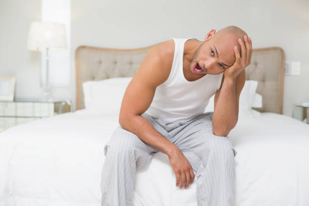 istock Bald man sitting and yawning in bed 852407820