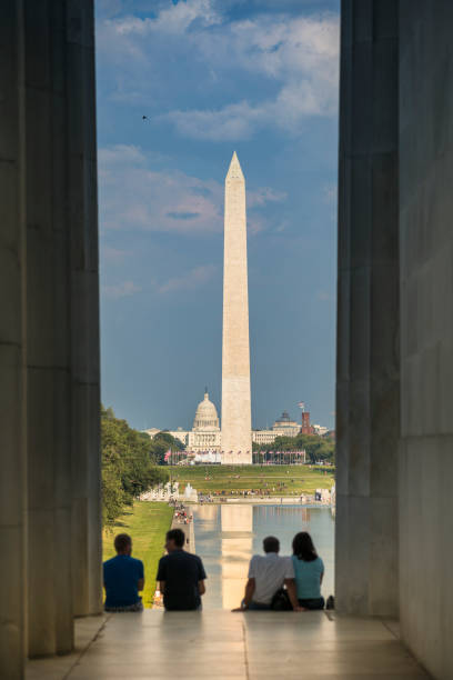 Washington Monument from the Lincoln Memorial Washington Dc: Washington DC Monument and the US Capitol Building and grounds viewed across the reflecting pool from the Lincoln Memorial on The National Mall USA.  The Washington Monument is an obelisk on the National Mall in Washington, D.C., built to commemorate George Washington, once commander-in-chief of the Continental Army and the first President of the United States. Located almost due east of the Reflecting Pool and the Lincoln Memorial, the monument, made of marble, granite, and bluestone gneiss, washington dc slavery the mall lincoln memorial stock pictures, royalty-free photos & images