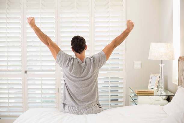 istock Rear view of man stretching his arms in bed 852412366