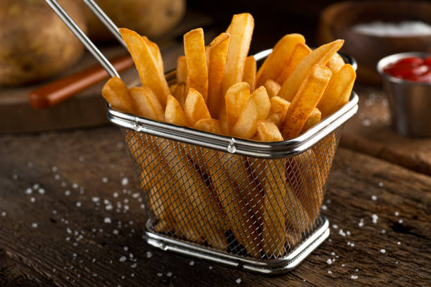 French Fries Crispy delicious french fries in a fryer basket. gold potato stock pictures, royalty-free photos & images