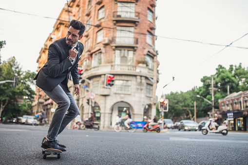 Young businessman riding skateboard on the street