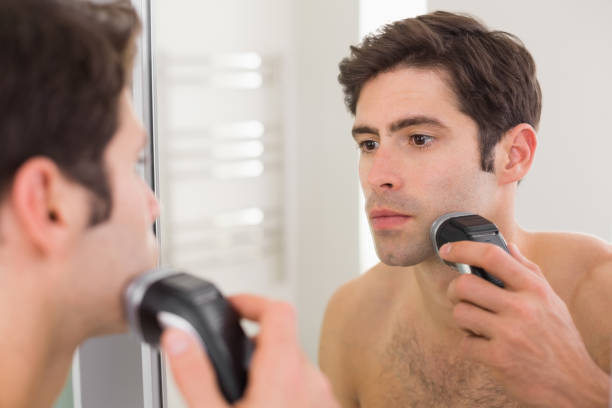 reflection of shirtless man shaving with electric razor - shaving men electric razor reflection imagens e fotografias de stock
