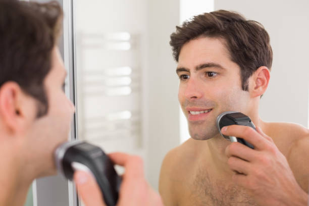 reflection of shirtless man shaving with electric razor - shaving men electric razor reflection imagens e fotografias de stock