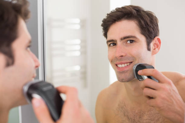 riflesso di uomo a torso a torso libero che si rade con rasoio elettrico - shaving men electric razor reflection foto e immagini stock