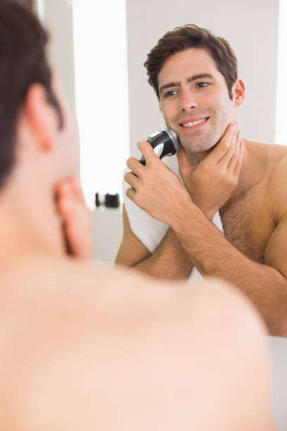reflection of shirtless man shaving with electric razor - shaving men electric razor reflection imagens e fotografias de stock