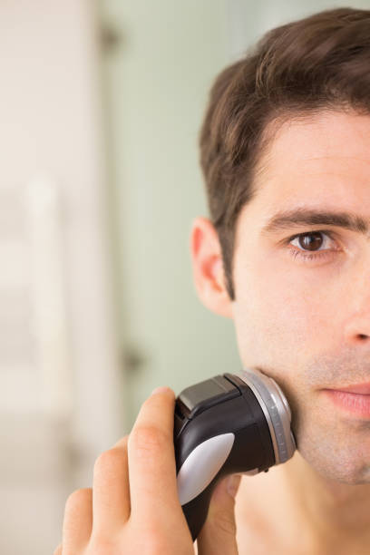 istock Handsome man shaving with electric razor 852418526