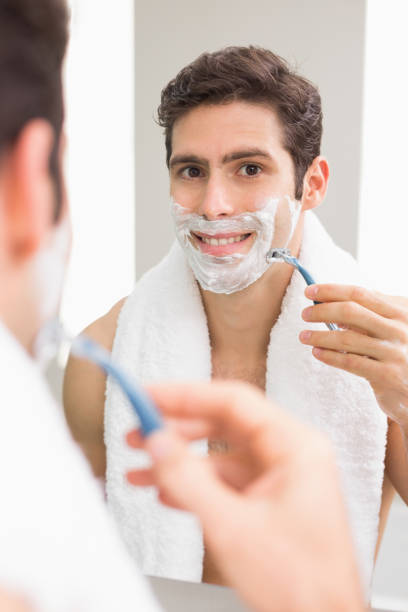 istock Young man with reflection shaving in bathroom 852419754