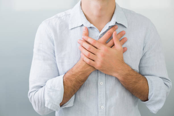 Mid section of a man with chest pain Close up mid section of a young man with chest pain man-hand-on-chest stock pictures, royalty-free photos & images