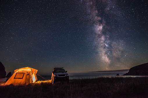 Tourist camping at sea coast at night with milky way. Some noise from hugh iso exists