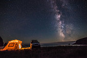 Tourist camping at sea coast at night with milky way