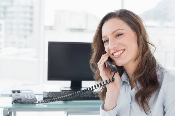 istock Smiling businesswoman using phone in front of computer 852442976