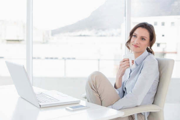 istock Businesswoman with laptop drinking coffee in office 852443140