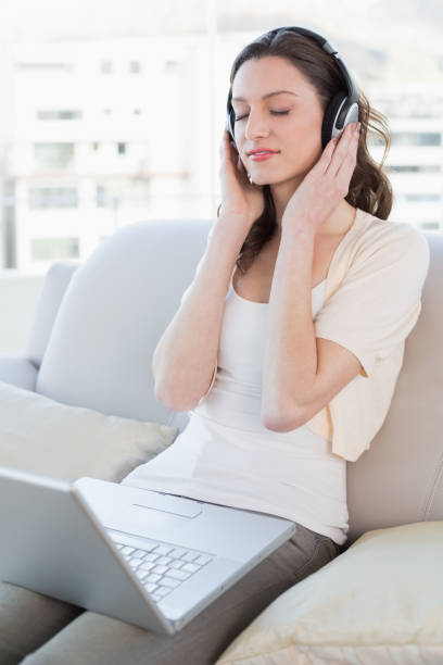 istock Relaxed woman with laptop enjoying music on sofa 852446054