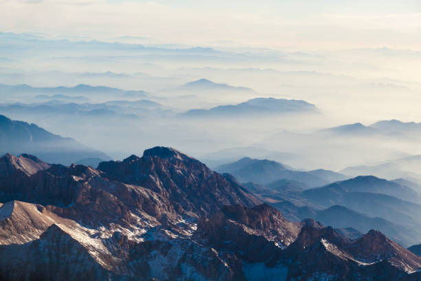 Aerial view of mountains and clouds through airplane window Aerial view of mountains and clouds through airplane window stratosphere airplane cloudscape mountain stock pictures, royalty-free photos & images