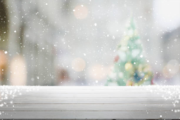 istock Wood table top on blur with bokeh christmas tree background with snowfall - can be used for display or montage your products 852464142