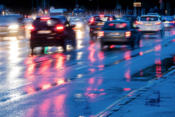 istock cars driving on wet road with headlights 852475412