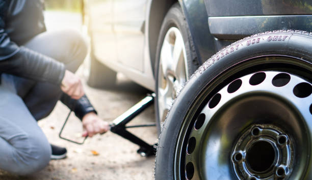 Driver changing spare tyre after accident. Broken and flat car wheel after crash. Man fixing problem with jack. Driver changing spare tyre after accident. Broken and flat car wheel after crash. flat tire stock pictures, royalty-free photos & images