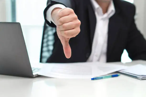 Photo of Business man showing thumbs down in office.