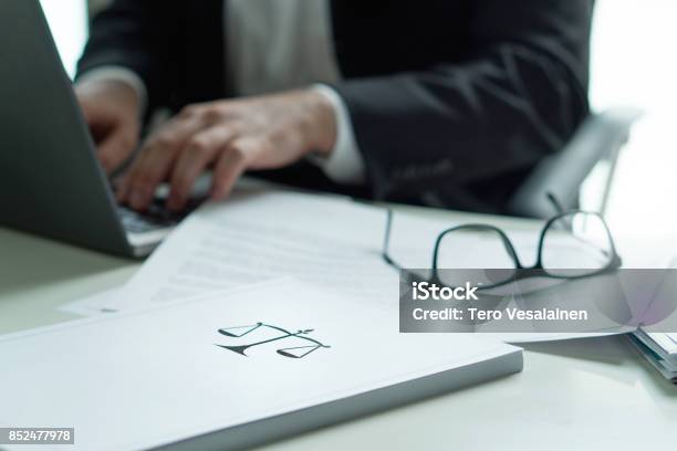 Lawyer Working In Office Attorney Writing A Legal Document With Laptop Computer Glasses On Table Pile Of Paper With Scale And Justice Symbol Law Firm And Business Concept Stock Photo - Download Image Now