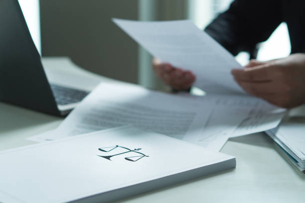 Man holding a legal document in hand. Lawyer holding law paper in office. Scale and justice symbol. stock photo