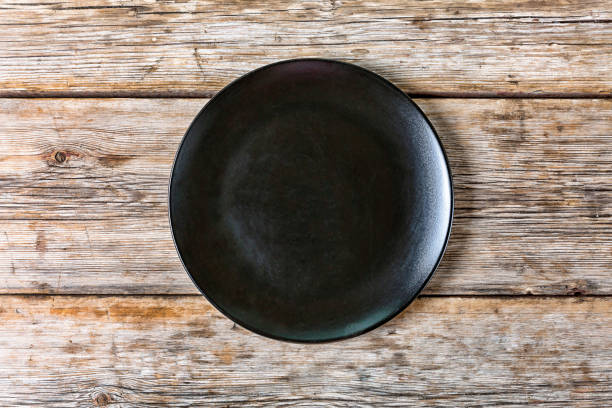 istock Empty black plate on an old wooden background. Top view, closeup. 852481004