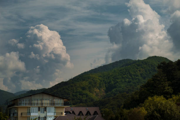 great white clouds over the mountains with the forest and the roofs of hotels