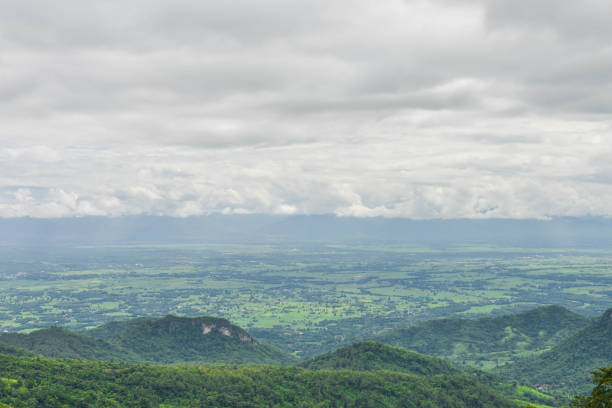 A picturesque view of lush green hills rolling beneath a sky adorned with dramatic clouds and vibrant blue tones. A winding road gently curves through the peaceful countryside, leading the viewer’s eyes deeper into the tranquil scene. The vibrant contrast of the greenery with the expansive sky creates a sense of calm and natural beauty, making this landscape perfect for projects focused on travel, nature, and scenic views.
