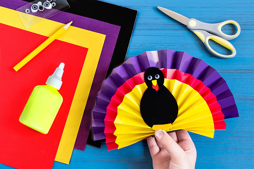Making souvenir for Thanksgiving: turkey made of paper. Original children's art project. DIY concept. Step-by-step photo instructions. Step 8. Child glues together all elements of souvenir turkey