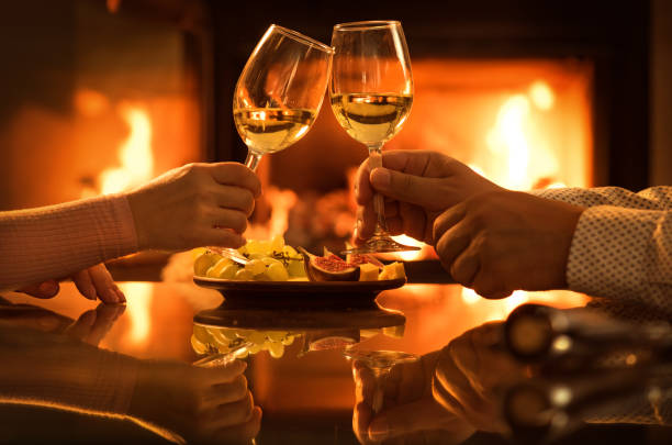 Young couple have romantic dinner with wine over fireplace background. stock photo