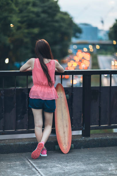 Young Woman With Skateboard Watching City