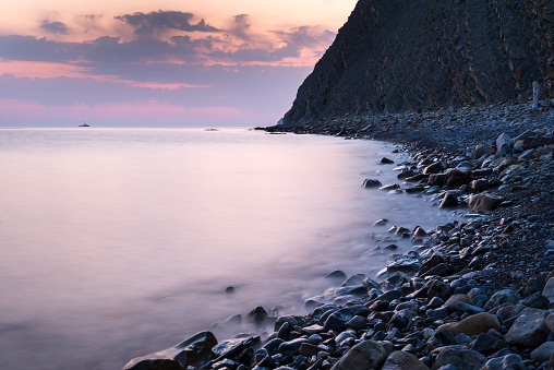 Magenta sunset on tropical beach slowshutter speed milkwater surface. Black Sea coast.
