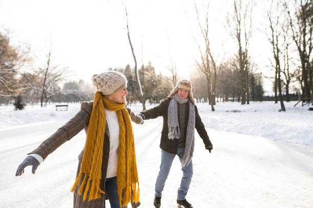 casal sênior no inverno ensolarado natureza patinagem no gelo. - senior couple senior adult action retirement - fotografias e filmes do acervo