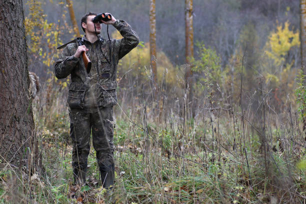 istock Man in camouflage and with guns in a forest belt on a spring hun 852675068