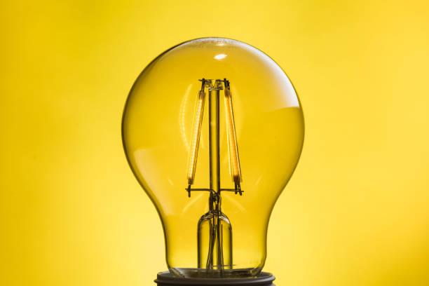 Close-up of an lluminated light bulb on a yellow background