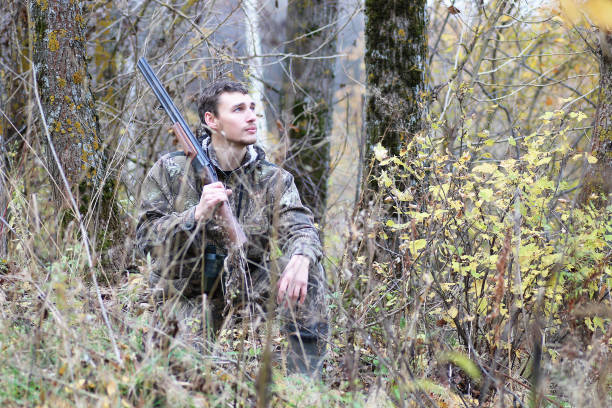 istock Man in camouflage and with guns in a forest belt on a spring hun 852678382