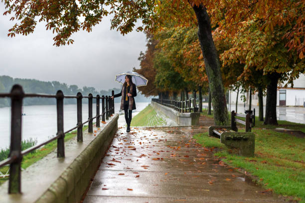 istock Young woman with umbrella walking beside river 852686150