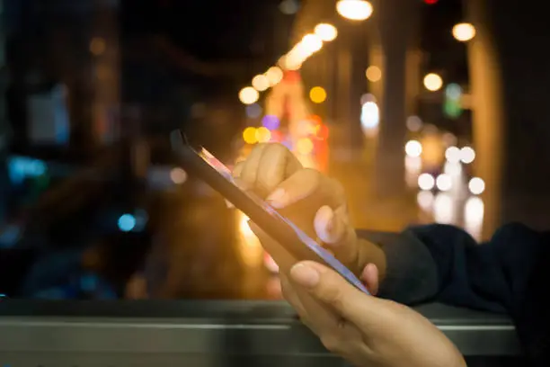Woman  touch screen  smartphone on blurred night-lights