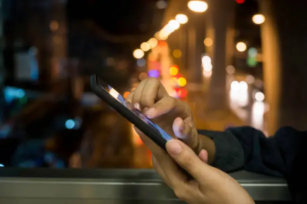 Woman  touch screen  smartphone on blurred night-lights