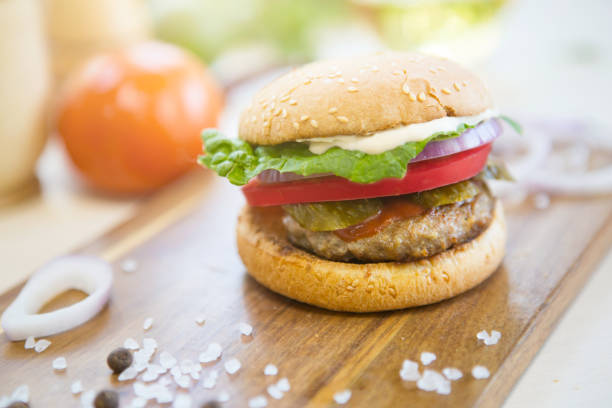 istock Appetizing hamburger on wooden cutting board. Pickles, onion, and cheddar cheese 852711578