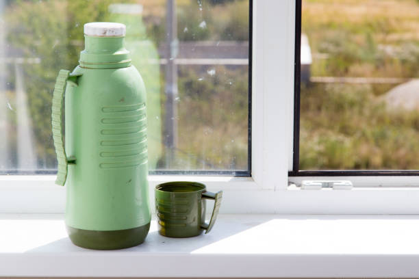istock thermos with a glass on the window 852711702