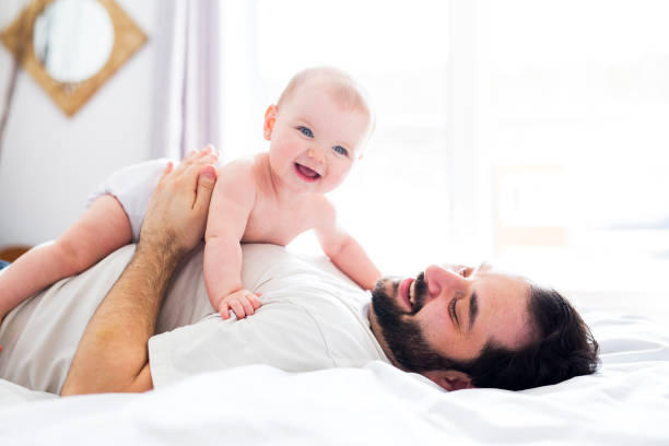 istock Young happy father playing with babyon bed 852733118