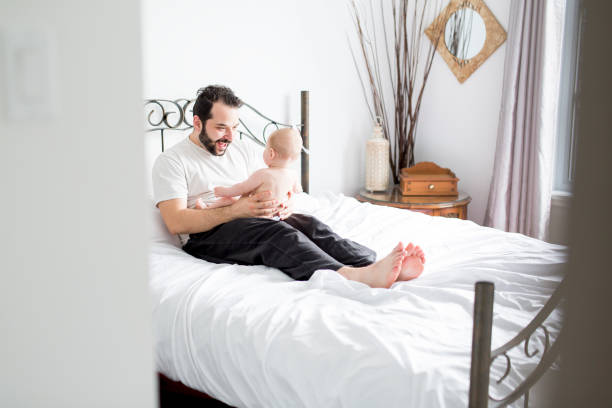 istock Young happy father playing with babyon bed 852740196