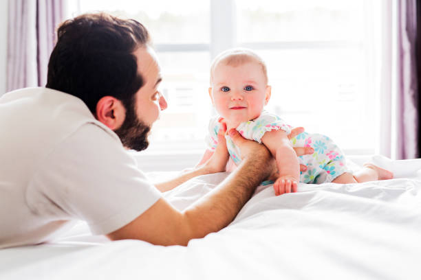 istock Young happy father playing with babyon bed 852742698