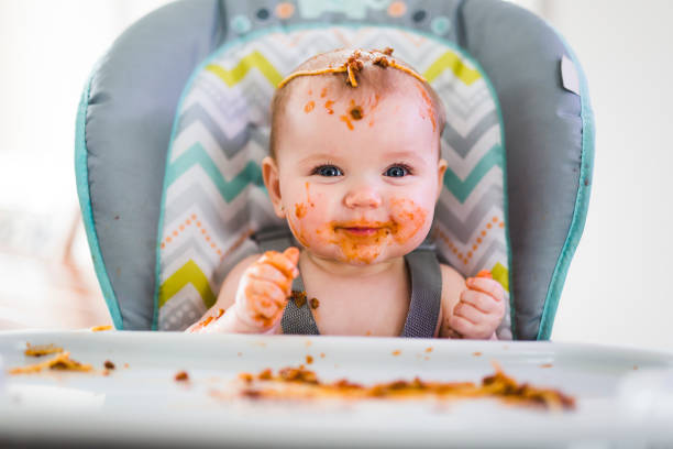 małe dziecko jedząc jej obiad i robiąc bałagan - baby food zdjęcia i obrazy z banku zdjęć