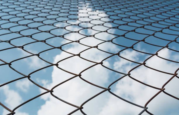 istock Rusty chain link fence under the sky background. Abstract closeup of a chain link sky background. 852749606