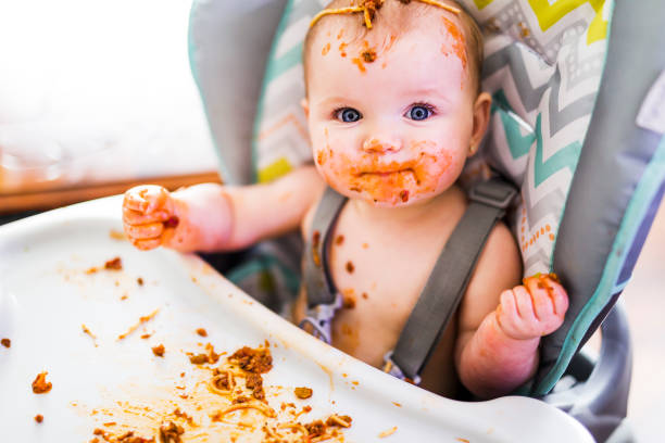 A Little baby eating her dinner and making a mess