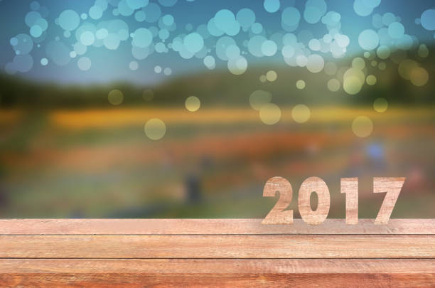 istock Empty wooden table and blurred flowers background with 2017.can be used for montage or display your products. 852753972