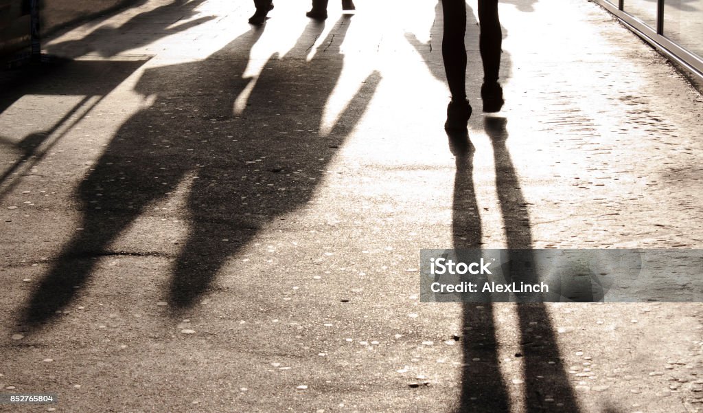 Blurry shadows and silhouettes on city sidewalk Blurry long shadows and silhouettes of people on the city sidewalk Crowd of People Stock Photo